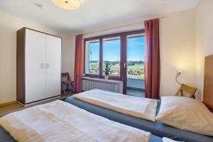 a bedroom with two beds and a large window at Lichtblick in Weiler-Simmerberg