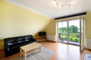a living room with a black leather couch and a television at Großes Ferienhaus mit Seeblick in Leezen