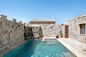 a swimming pool in a stone building with a waterfall at Loft Abanderao Piscina y Jacuzzi in Conil de la Frontera