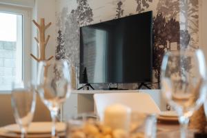 a table with glasses on a table with a television at Le Banc des Hermelles in Saint-Benoît-des-Ondes