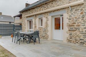 a patio with a table and chairs in front of a building at Le Banc des Hermelles in Saint-Benoît-des-Ondes