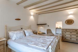 a bedroom with a white bed and a dresser at Mrs Kalis cottage in Andros