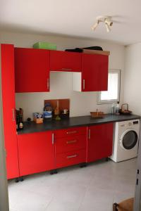 a kitchen with red cabinets and a washing machine at Gite Chez Jeanne in Pern