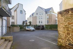 a parking lot with two cars parked in front of buildings at Urania - Escale centre Concarneau in Concarneau