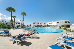 a group of people laying in lounge chairs by a pool at Club Atlantis 159 in Adeje