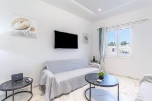 a white living room with a couch and a tv at Corfu Haven in Ágios Rókkos