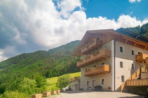 a building with wooden balconies on the side of it at Planerhof Apartment Lilie in Funes