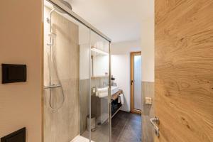 a bathroom with a glass shower with a sink at Planerhof Apartment Lilie in Funes +29 photos