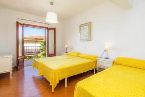 two beds in a room with yellow sheets at Gran Vista Mar in Alcudia +25 photos