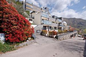 a building on a bridge with red flowering bushes at Relax and Happiness private Jacuzzi in Perledo