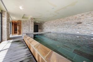a swimming pool in a room with a brick wall at Relax and Happiness private Jacuzzi in Perledo