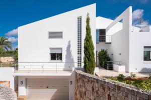 a white house with a stone wall at Villa Xipell 9 in Cala Santandria