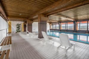 a pool with white chairs and a swimming pool at Terrassenpark Apartment 160 in Schonach