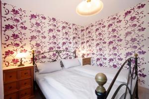 a bedroom with a bed with purple floral wallpaper at Ferienwohnung Schoeneberg in Vogt