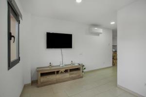 a living room with a television on a white wall at Edificio Bentejui 1 in Las Palmas de Gran Canaria