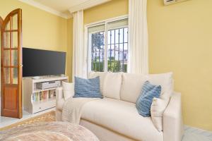 a living room with a white couch with blue pillows at Vakantiewoning Torrox Park 300 in Torrox
