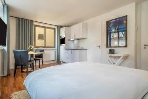 a bedroom with a large white bed and a kitchen at 1 Zimmer-appartment Nr 11 in Wangen im Allgäu