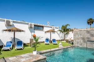 a house with a swimming pool with chairs and umbrellas at Casa Mirajanda in Vejer de la Frontera