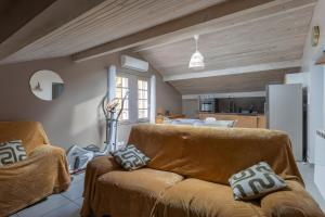 a living room with a brown couch and a kitchen at Maison Xara-heguia in Hasparren