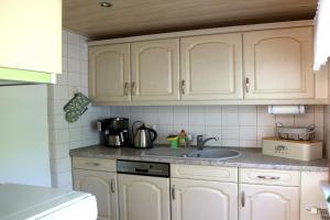 a kitchen with white cabinets and a sink at Haus Waldidyll am Briesensee in Neu Zauche
