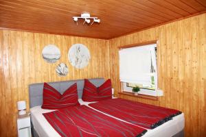 a bedroom with a bed with red pillows and a window at Haus Waldidyll am Briesensee in Neu Zauche