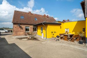 a yellow house with a table in front of it at Ferienhaus Hedrich in Gülzow