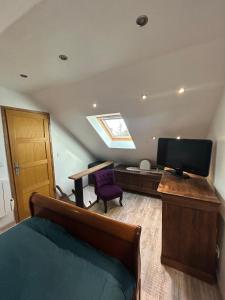 a bedroom with a bed and a desk and a television at Petit Duplex Proche Mer in Plouhinec