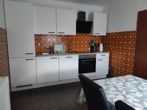 a kitchen with white cabinets and a sink and a table at Ferienwohnung Buedinger Weg in Gründau