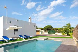 a house with a swimming pool and two chairs and an umbrella at Villa Montenmedio - Paula in El Soto