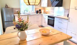 a kitchen with a wooden table with a vase of flowers at Gittas Paradiesperle in Niederdreisbach