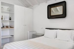 a bedroom with a white bed with a mirror on the wall at Casa do Mestre Studio e Suíte Extra in Vila de Punhe +22 photos