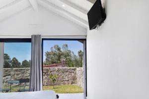 a living room with a tv and a window at Casa do Mestre Studio e Suíte Extra in Vila de Punhe