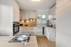 a kitchen with white cabinets and a table with a chair at Ferienwohnung K5 in Wehr