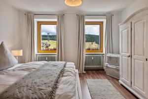 a bedroom with a large bed and two windows at Haus Bergruh Kuckucksnest in Todtnauberg