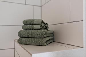 a stack of green towels sitting on a shelf in a bathroom at Haus Bergruh Kuckucksnest in Todtnauberg +25 photos