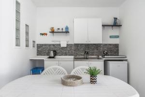 a kitchen with white cabinets and a table with a plant at Syrios Suites No 2 in Kalymnos +15 photos
