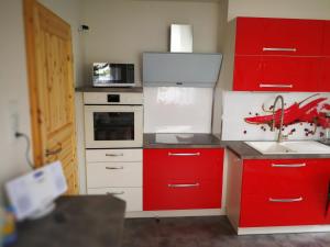 a red and white kitchen with a sink and a microwave at Ferienwohnung am Silberg in Plettenberg