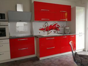 a red kitchen with a sink and red cabinets at Ferienwohnung am Silberg in Plettenberg +27 photos
