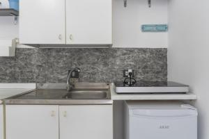 a kitchen with a sink and white cabinets at Syrios Suites No 2 in Kalymnos