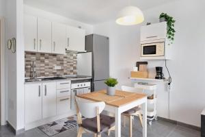 a kitchen with white cabinets and a table and chairs at Casa Paloma in Costa Teguise