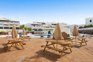 a group of picnic tables with umbrellas on a patio at Casa Paloma in Costa Teguise