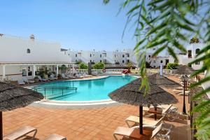 a swimming pool with chairs and umbrellas at Casa Paloma in Costa Teguise