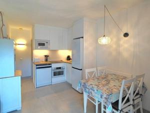 a kitchen with a table and a white refrigerator at Marlena in Cala en Bosc