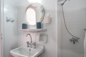a white bathroom with a sink and a mirror at Livadia Seaside Studios 13 in Parikia