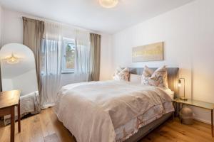 a white bedroom with a large bed and a table at bei Stefanie in Bad Koetzting