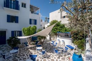 a patio with chairs and tables and a umbrella at Livadia Seaside Studios 13 in Parikia