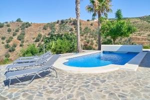 a swimming pool with lounge chairs and palm trees at Villa Amapola in Caserío Carraspite
