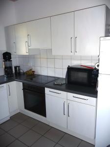 a kitchen with white cabinets and a black microwave at Maison Sulz in Montendre
