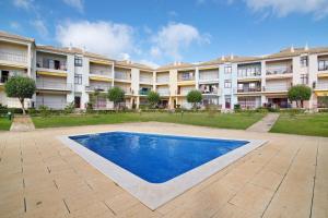 an apartment building with a swimming pool in front of it at Columbus Beach Apartment in Quarteira