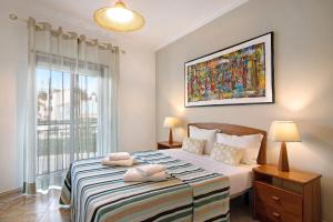 a bedroom with a large bed with two towels on it at Columbus Beach Apartment in Quarteira +17 photos